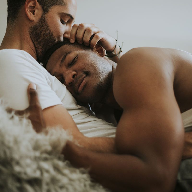 Gay couple cuddling in bed